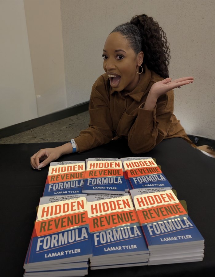 Crystal Swain-Bates with a stack of Lamar Tyler's Hidden Revenue Formula books